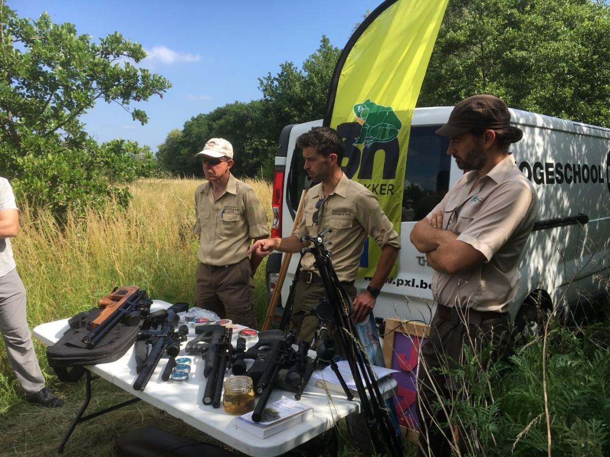 Experten van het Agentschap Natuur en Bos achter een tafel vol jachtgeweren