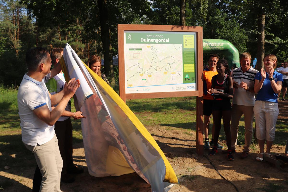 Mensen applaudisseren naast het infobord van natuurloop Duinengordel