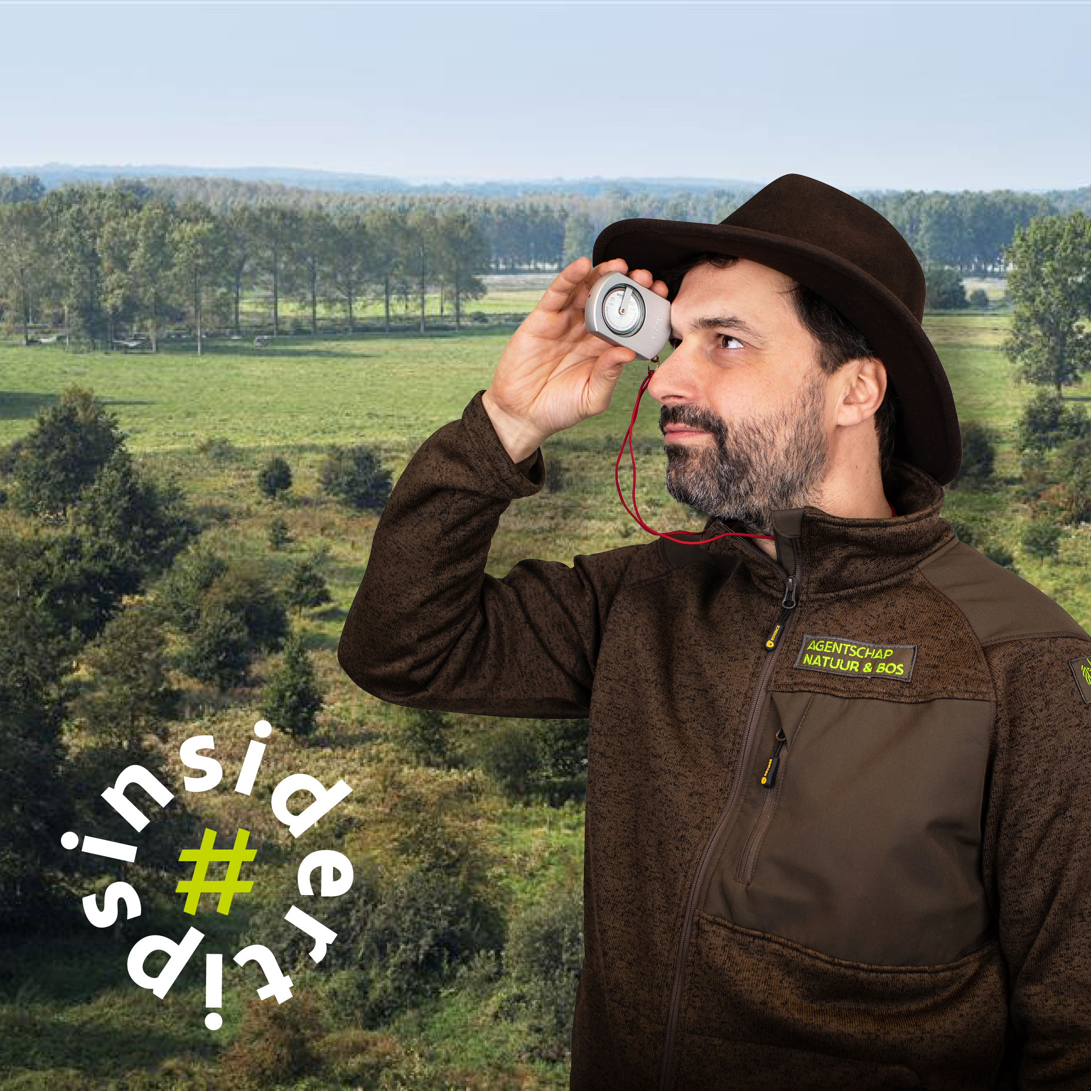 Boswachter Gijs die een digitale hoogtemeter voor zijn ogen houdt, met een bos op de achtergrond