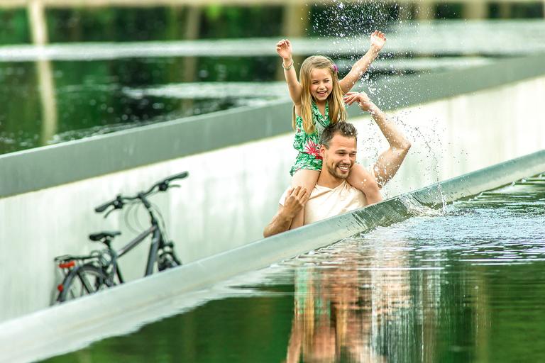 Vader en dochter fietsen door water