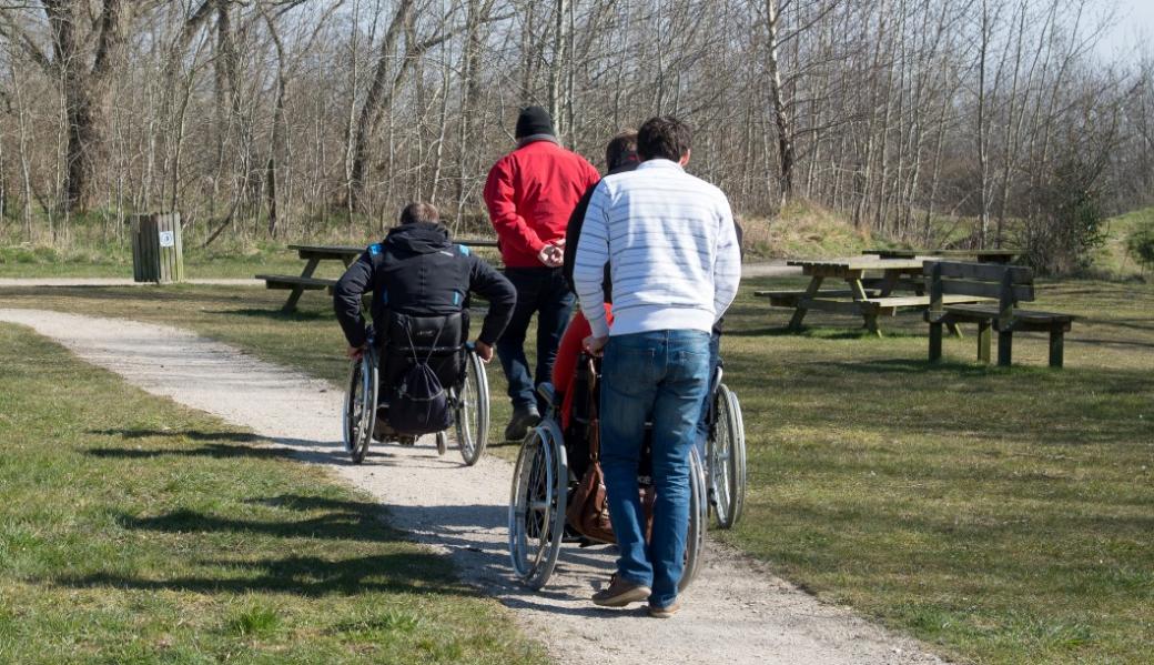 een klein groepje wandelaars met personen in een rolstoel